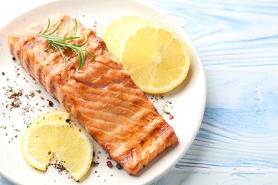 Photo of Delicious grilled salmon fillet served on light blue wooden table, closeup