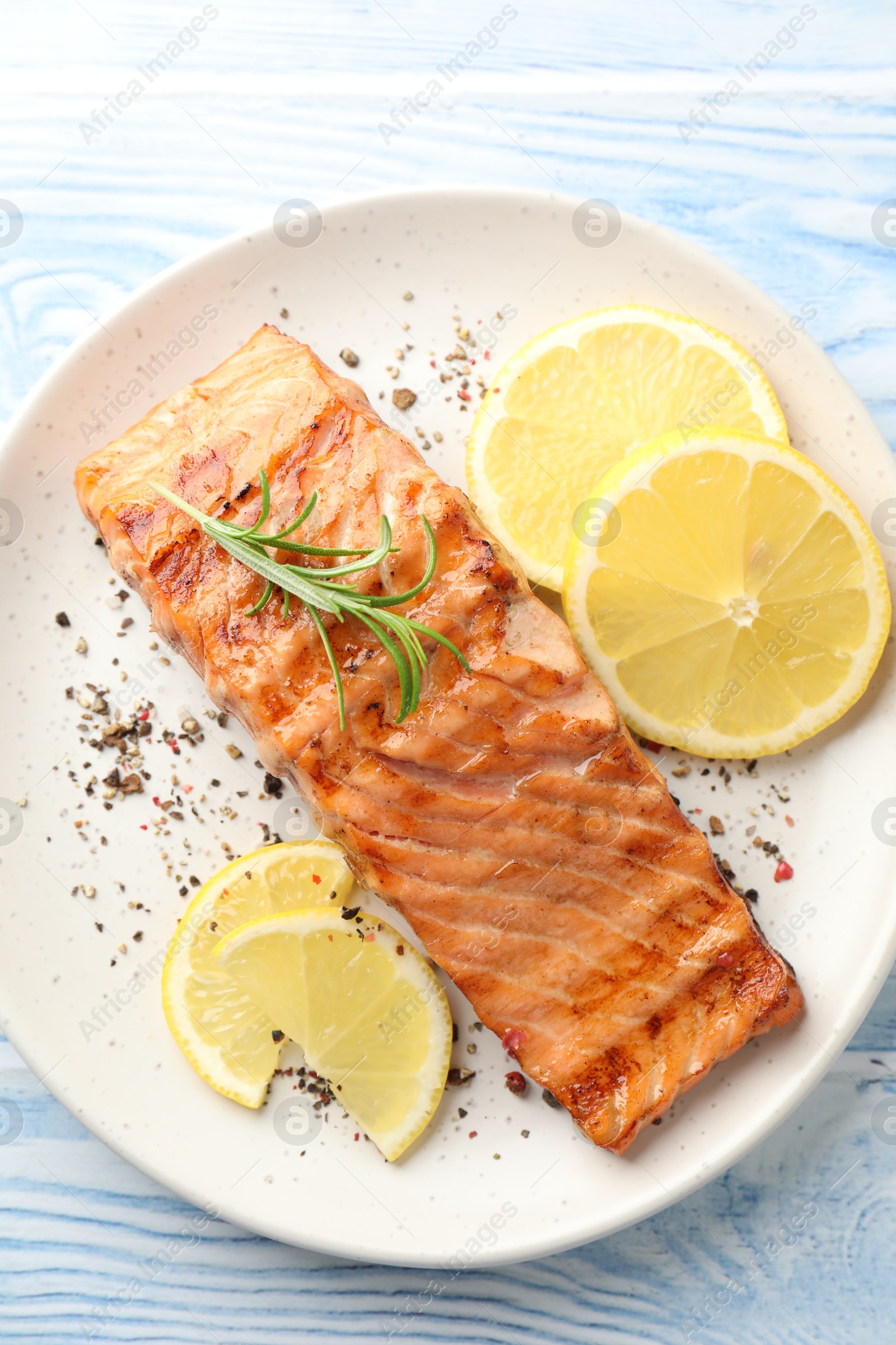 Photo of Delicious grilled salmon fillet served on light blue wooden table, top view