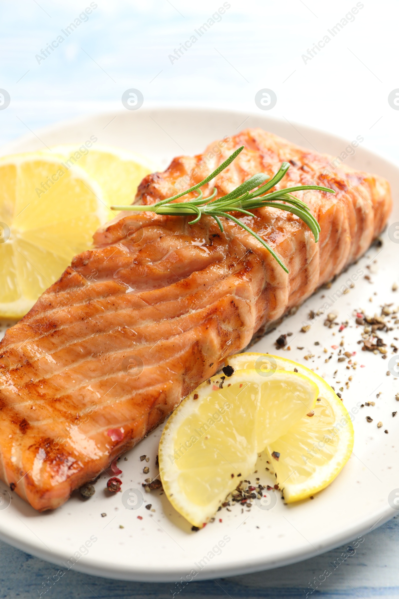 Photo of Delicious grilled salmon fillet served on light blue wooden table, closeup