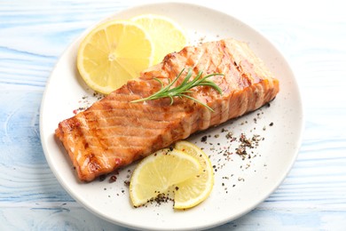 Photo of Delicious grilled salmon fillet served on light blue wooden table, closeup