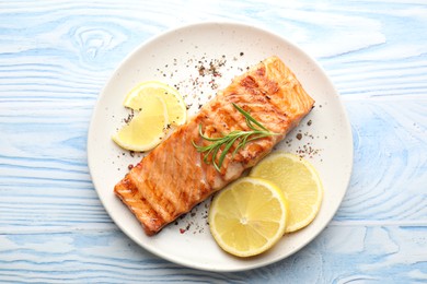 Delicious grilled salmon fillet served on light blue wooden table, top view