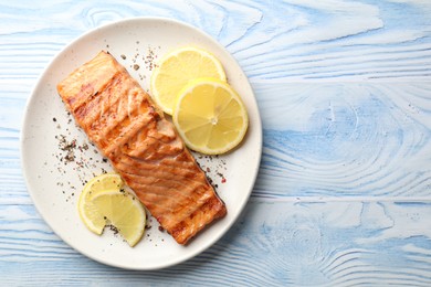 Photo of Delicious grilled salmon fillet served on light blue wooden table, top view