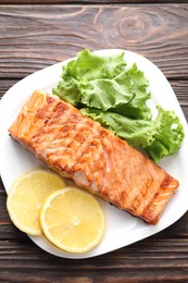 Delicious grilled salmon fillet served on wooden table, top view