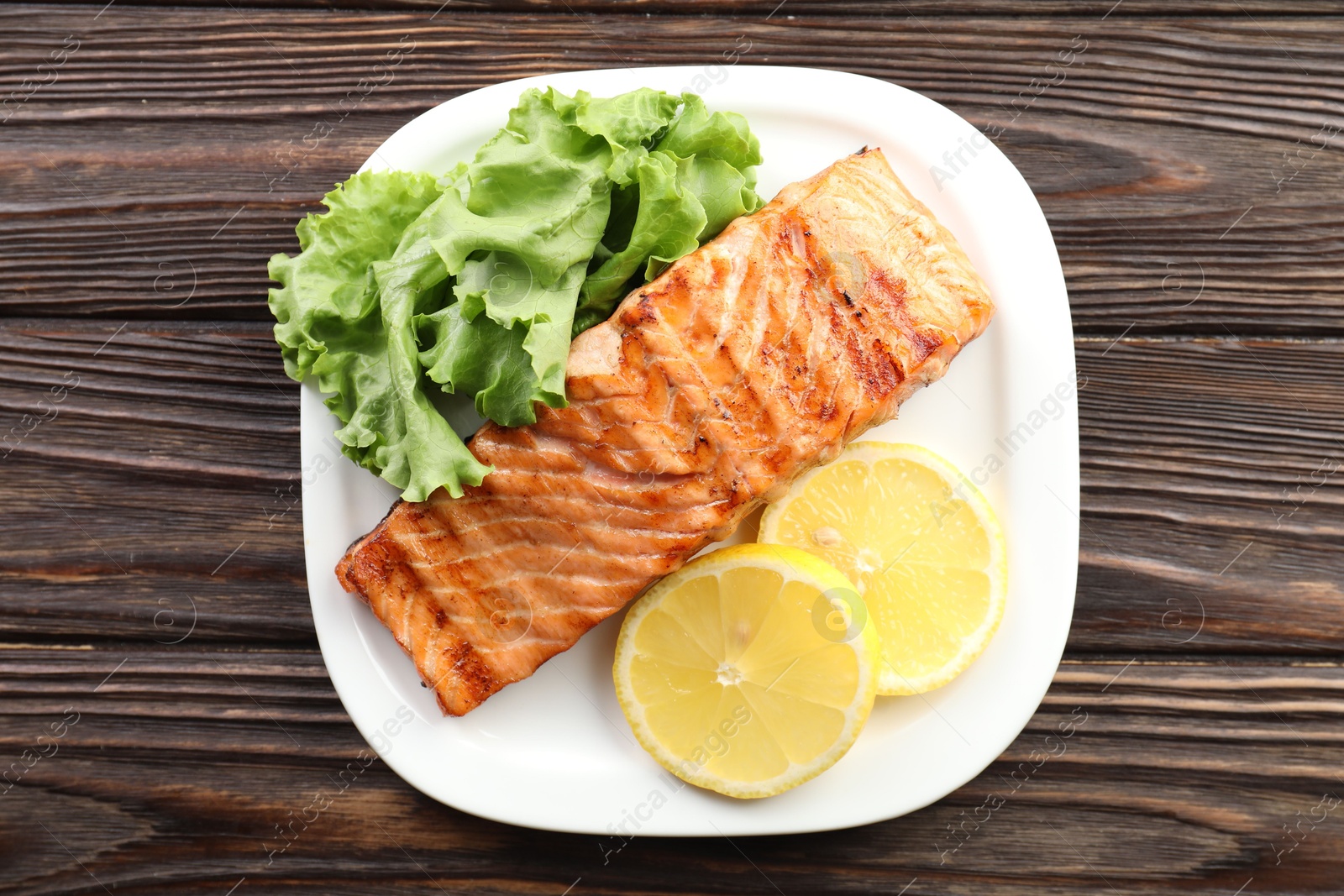 Photo of Delicious grilled salmon fillet served on wooden table, top view