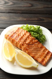 Delicious grilled salmon fillet served on wooden table, closeup