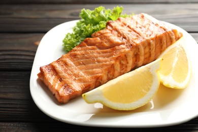 Photo of Delicious grilled salmon fillet served on wooden table, closeup