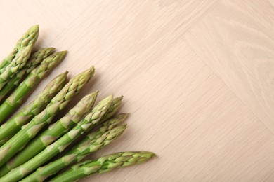 Photo of Fresh green asparagus stems on wooden table, top view. Space for text