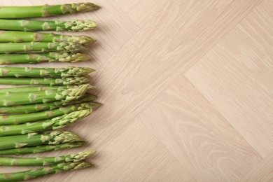 Photo of Fresh green asparagus stems on wooden table, top view. Space for text