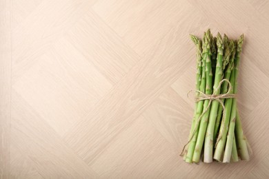 Photo of Bunch of fresh green asparagus stems on wooden table, top view. Space for text