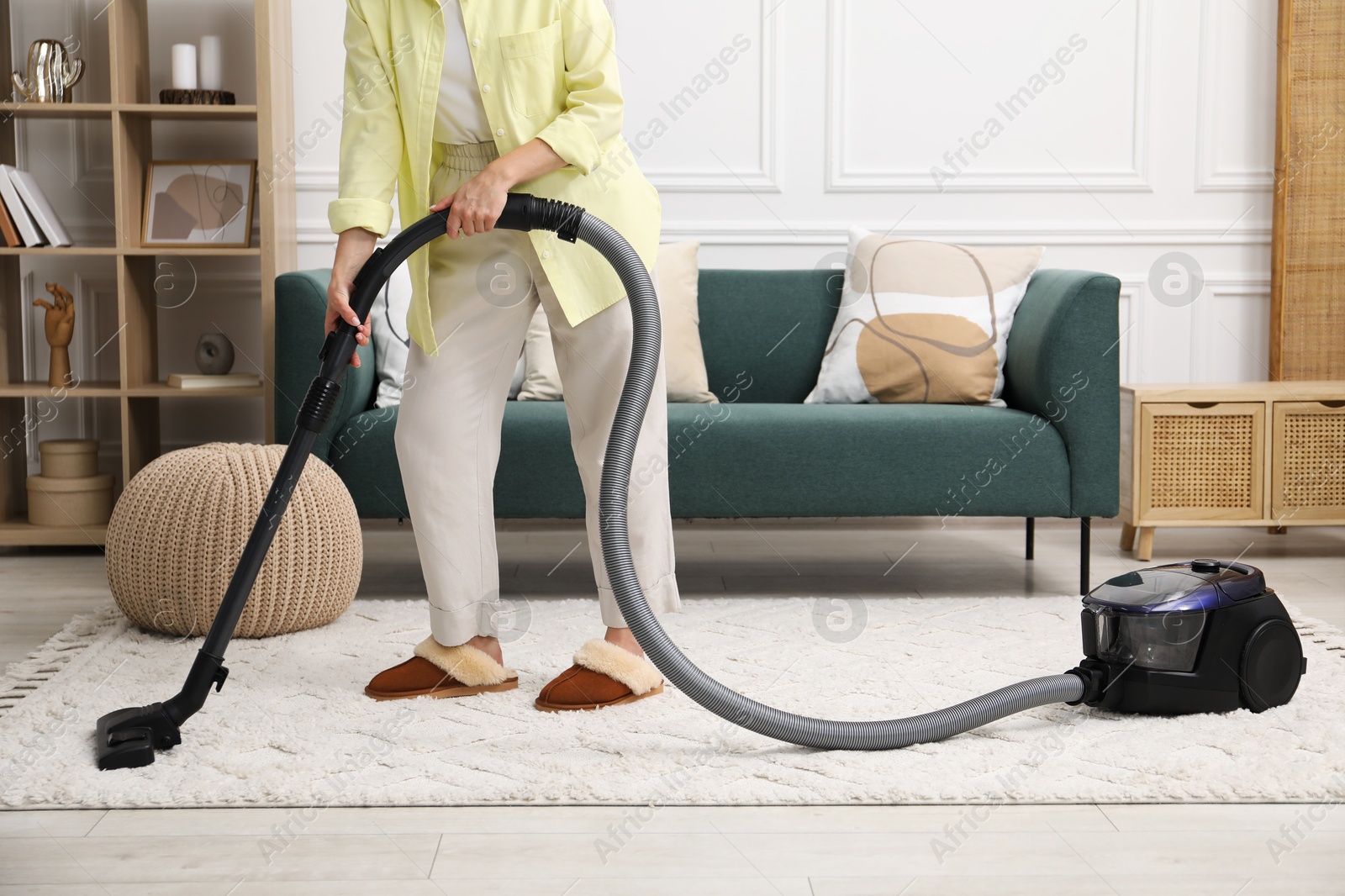 Photo of Woman cleaning carpet with vacuum in living room, closeup