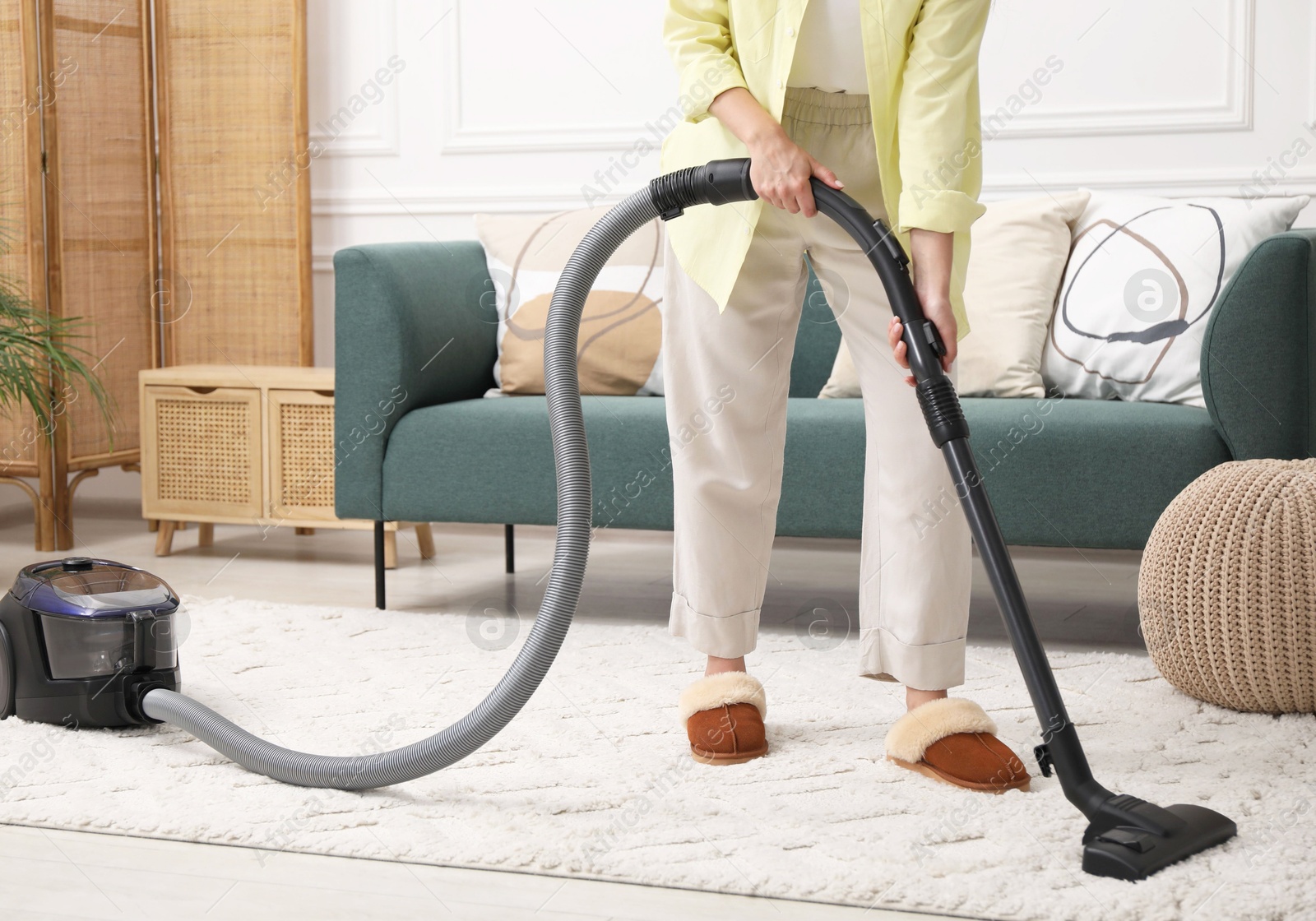 Photo of Woman cleaning carpet with vacuum in living room, closeup