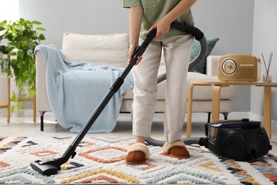 Photo of Woman cleaning carpet with vacuum in living room, closeup