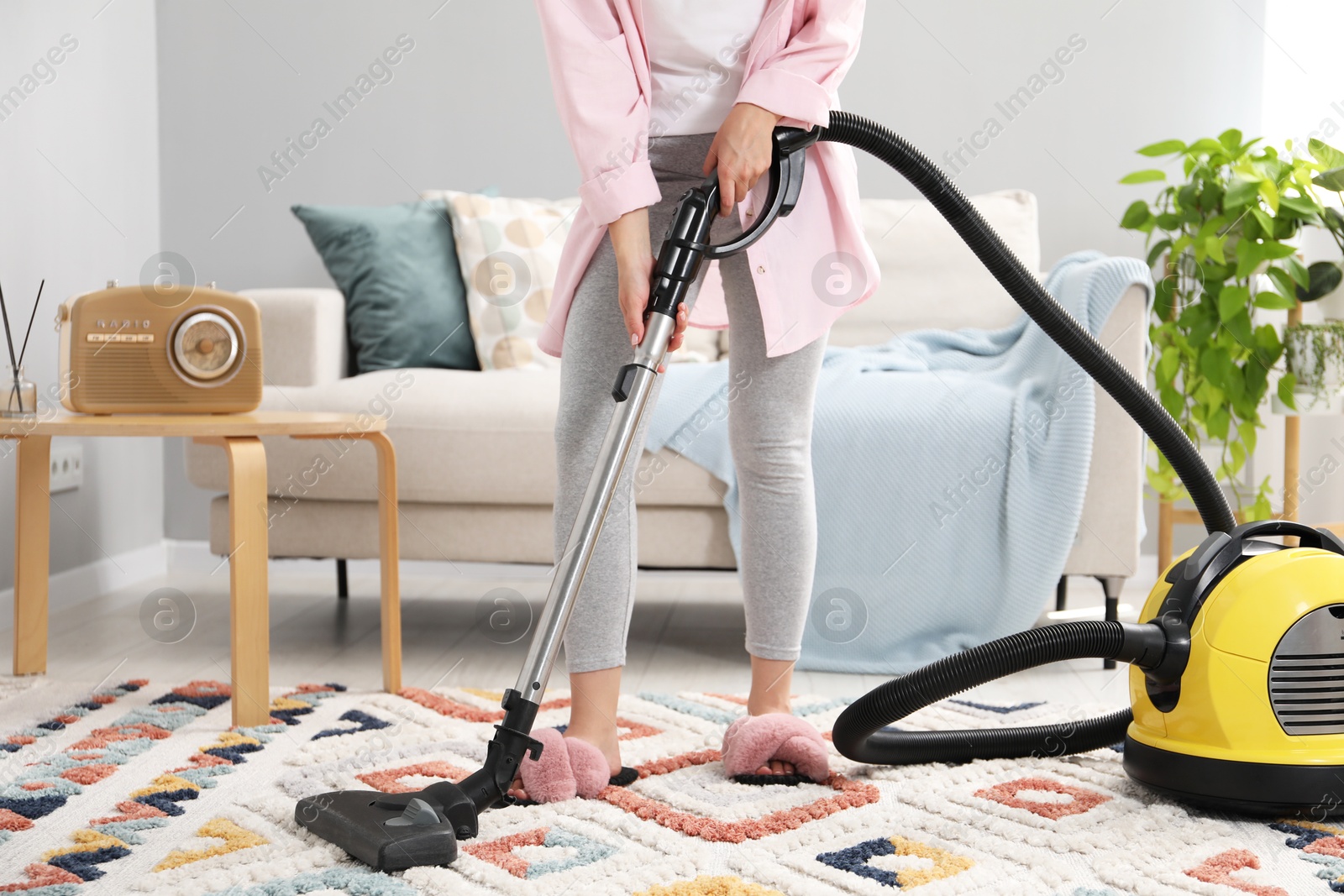 Photo of Woman vacuuming carpet in living room, closeup