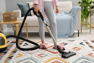 Photo of Woman vacuuming carpet in living room, closeup