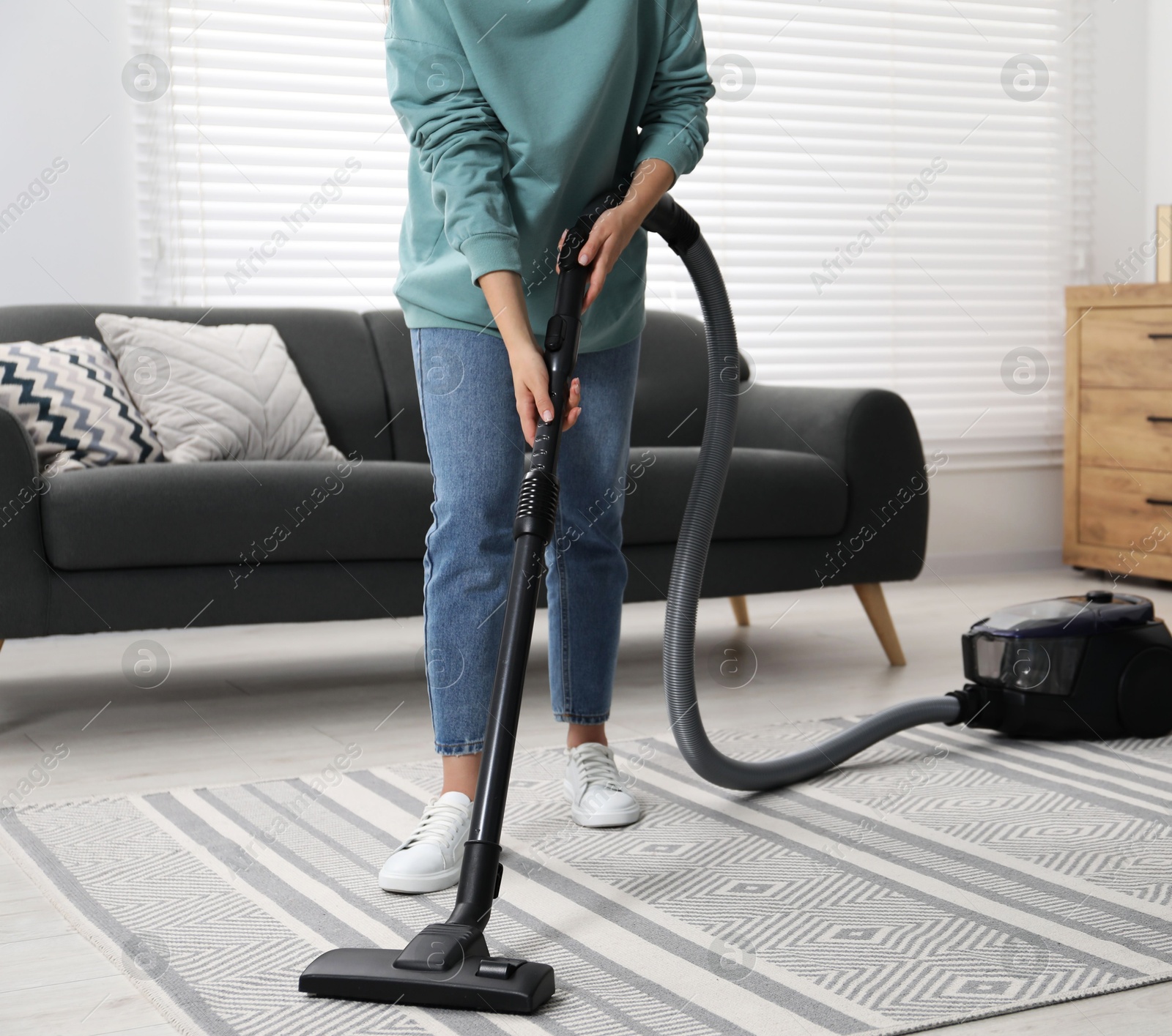 Photo of Woman vacuuming carpet at home, closeup view