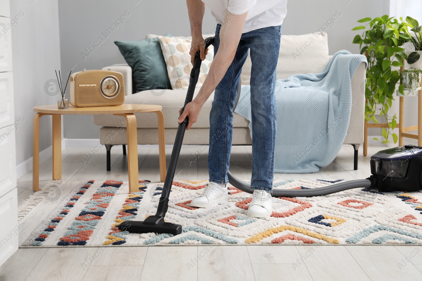 Photo of Man with vacuum cleaning carpet indoors, closeup