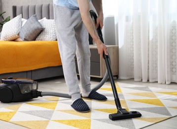 Photo of Man with vacuum cleaning carpet in bedroom, closeup