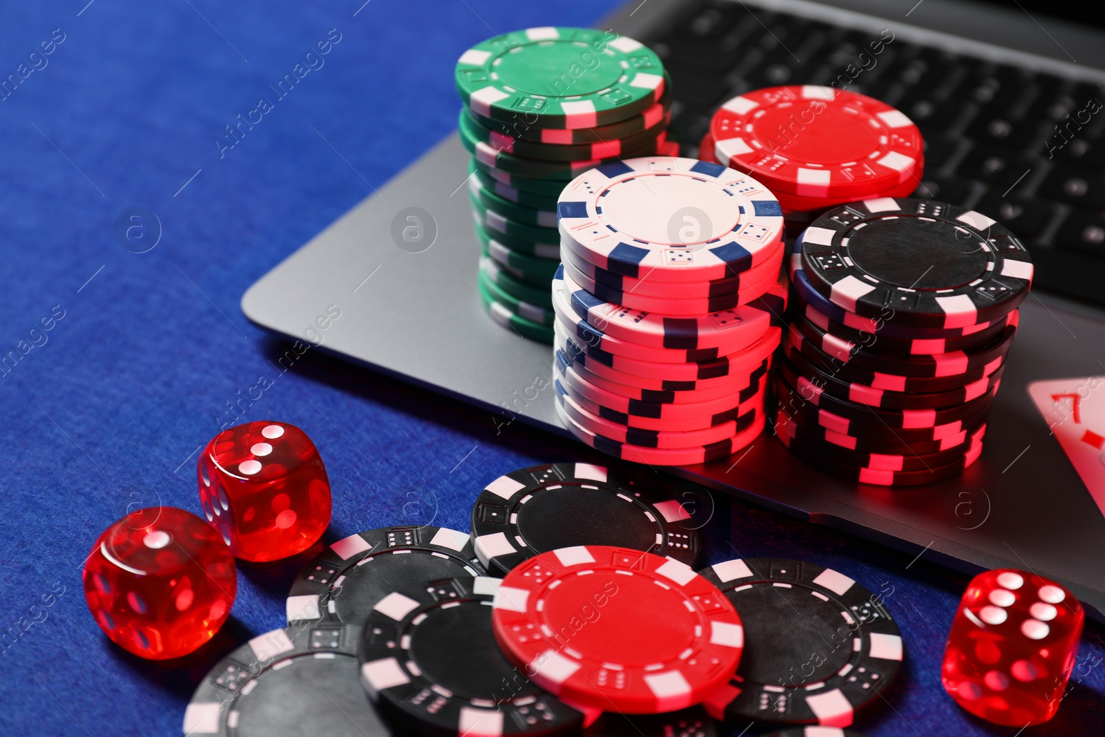 Photo of Poker chips, laptop and dices on blue table. Online game