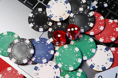 Photo of Poker chips, laptop and dices on red table, above view. Online game