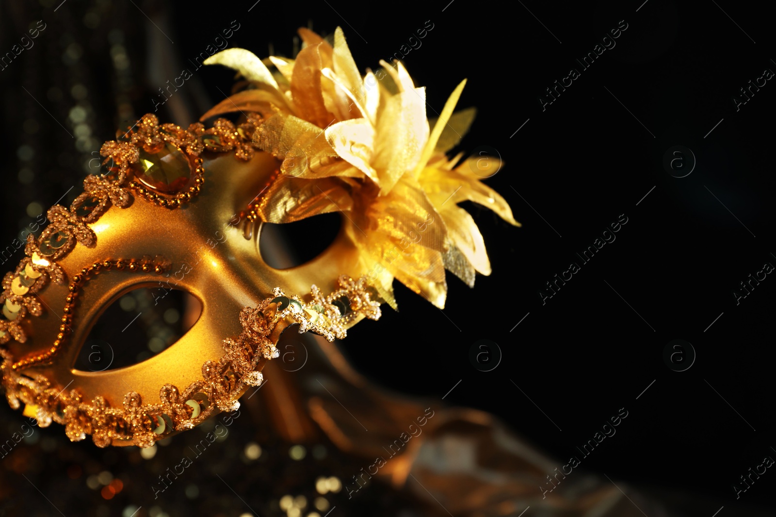 Photo of Beautiful golden carnival mask in darkness, closeup