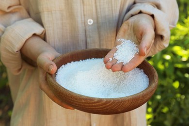 Photo of Woman holding plant fertilizer in bowl outdoors, closeup