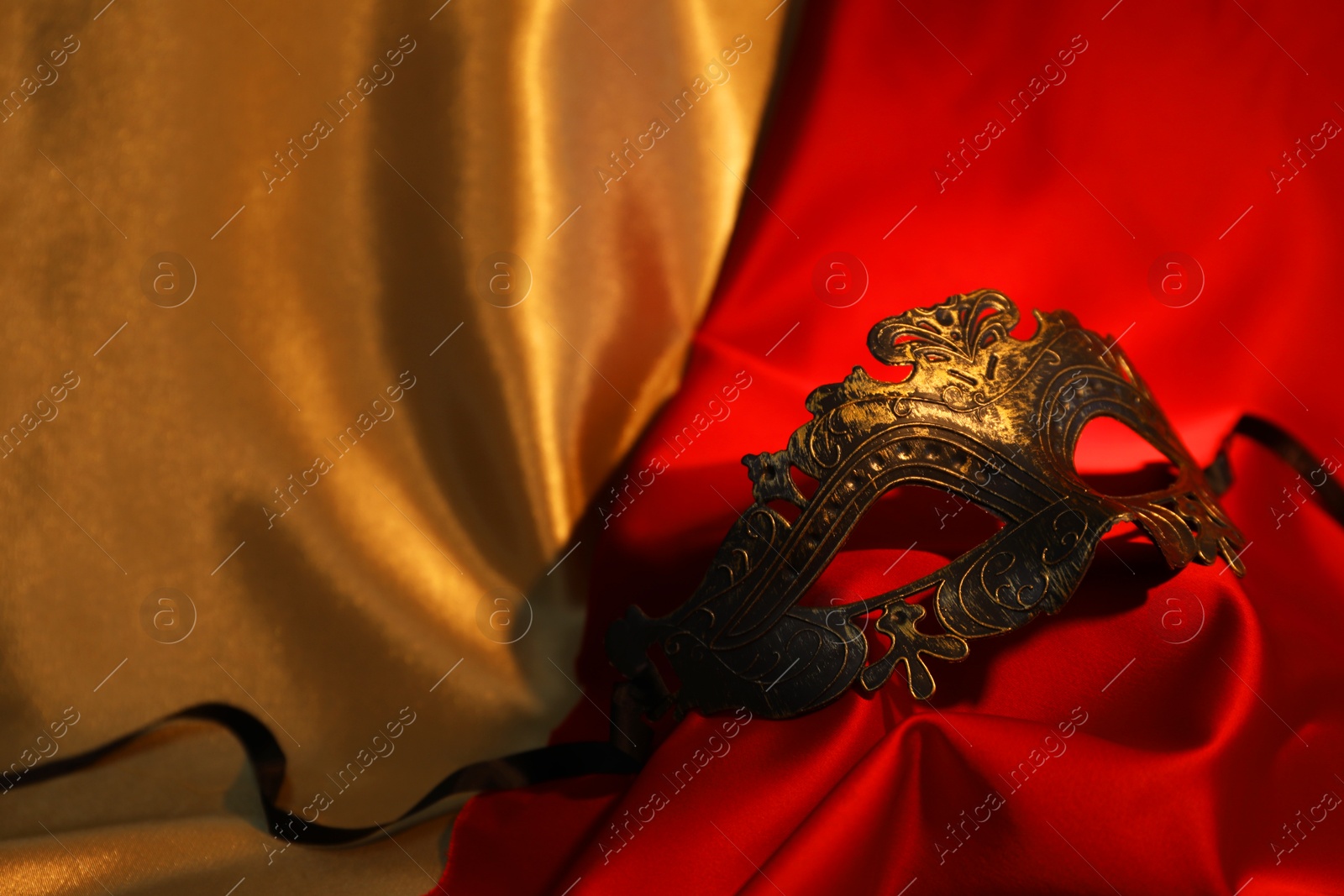 Photo of Beautiful carnival mask on silk fabric, closeup