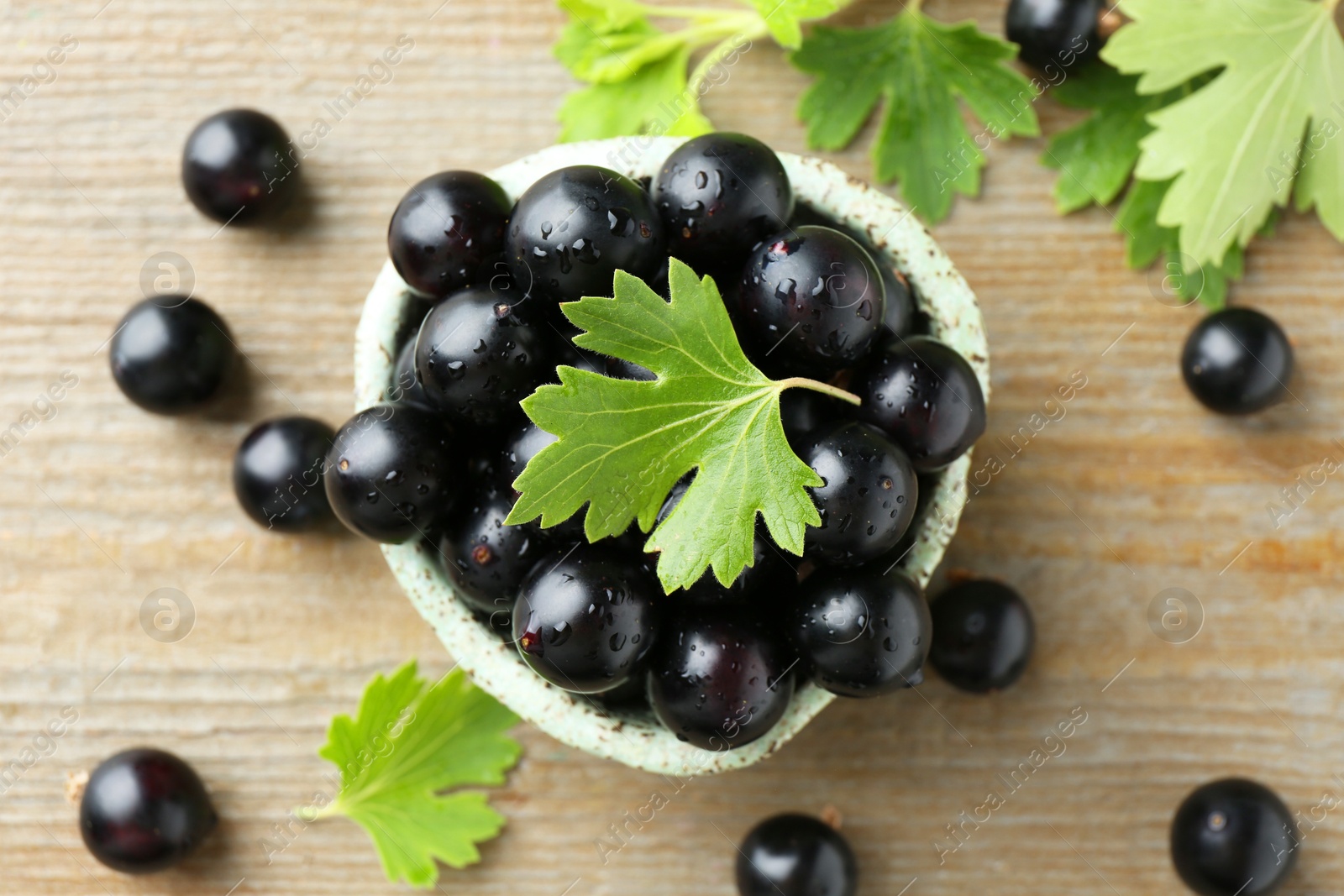 Photo of Fresh ripe black currant berries and leaves on wooden table, flat lay