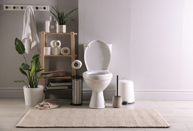 Photo of White toilet bowl, paper rolls and houseplants in bathroom, space for text