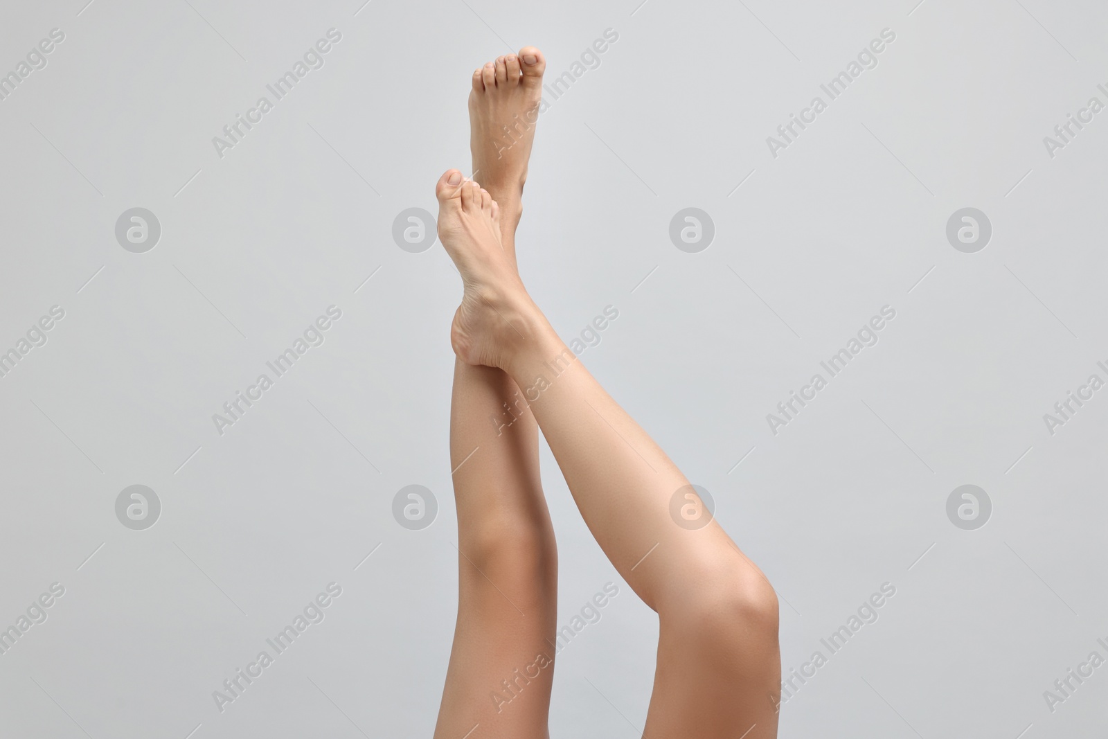 Photo of Woman with smooth legs on grey background, closeup