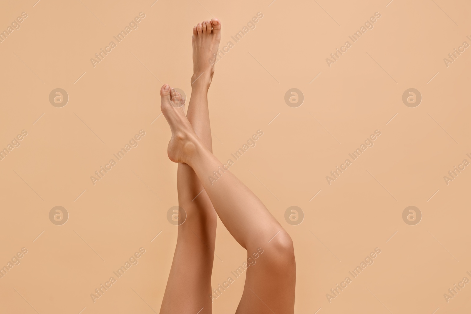 Woman with smooth legs on beige background, closeup Photo of Woman with smooth legs on beige background, closeup