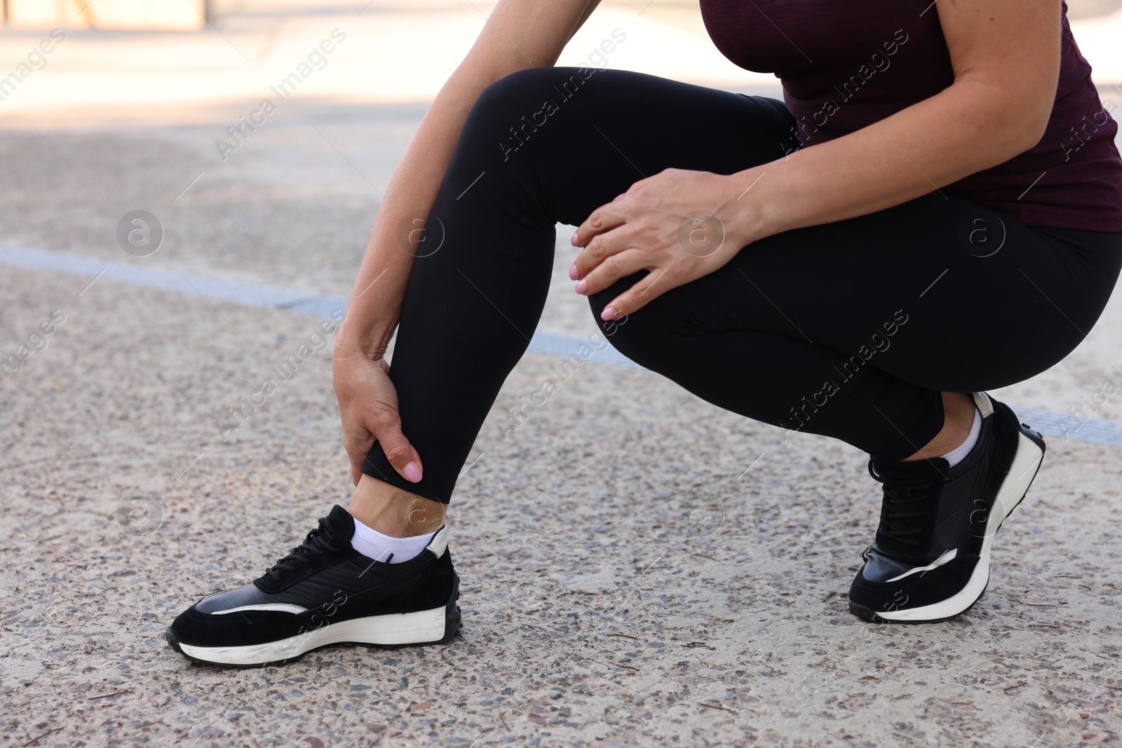 Photo of Woman suffering from foot pain outdoors, closeup