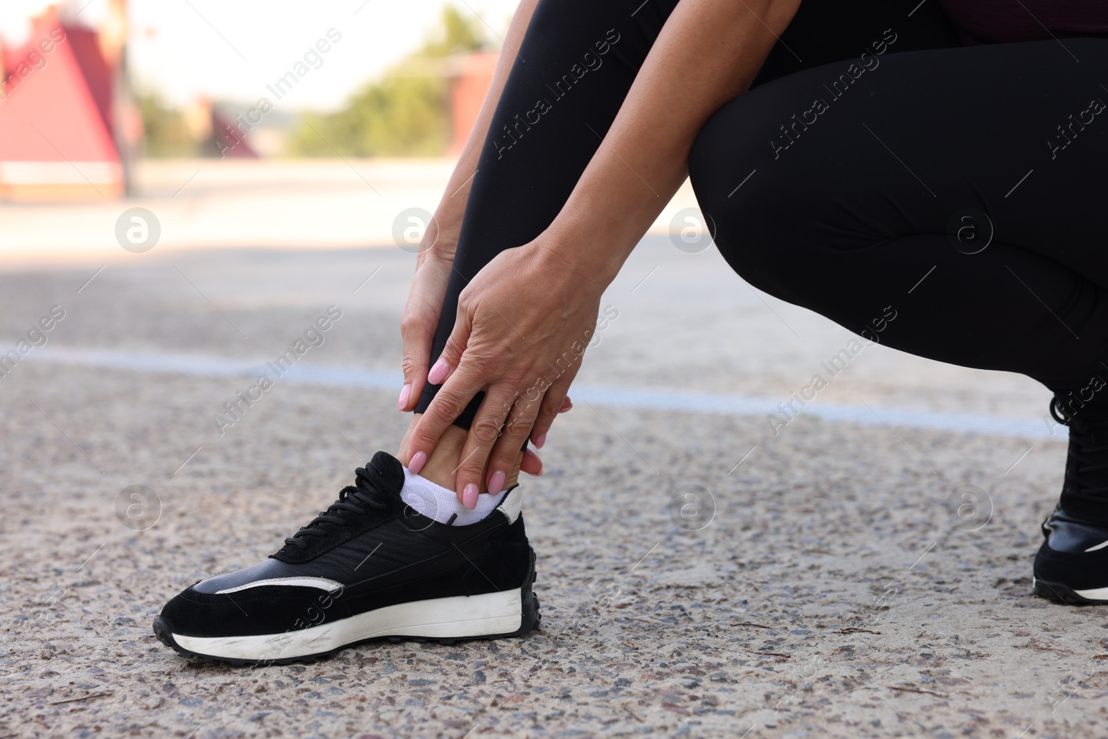 Photo of Woman suffering from foot pain outdoors, closeup