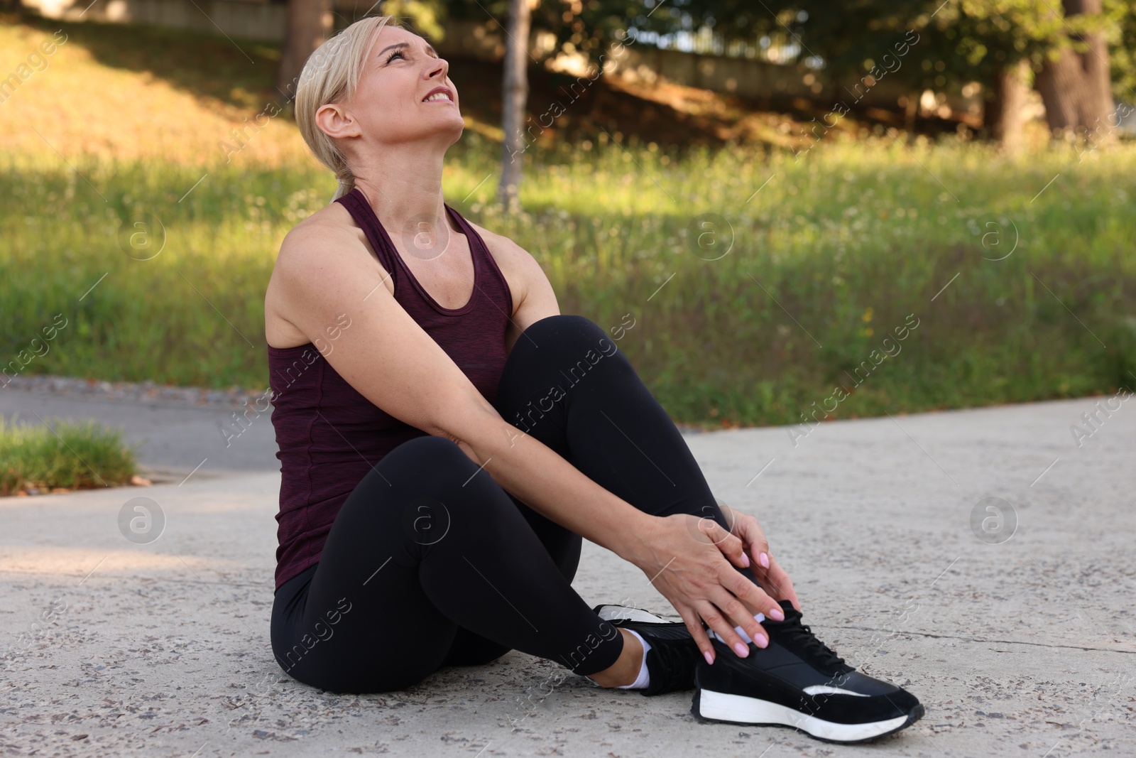 Photo of Sad woman suffering from foot pain outdoors