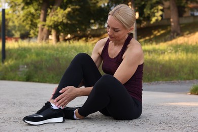 Sad woman suffering from foot pain outdoors