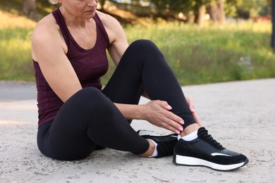 Photo of Woman suffering from foot pain outdoors, closeup