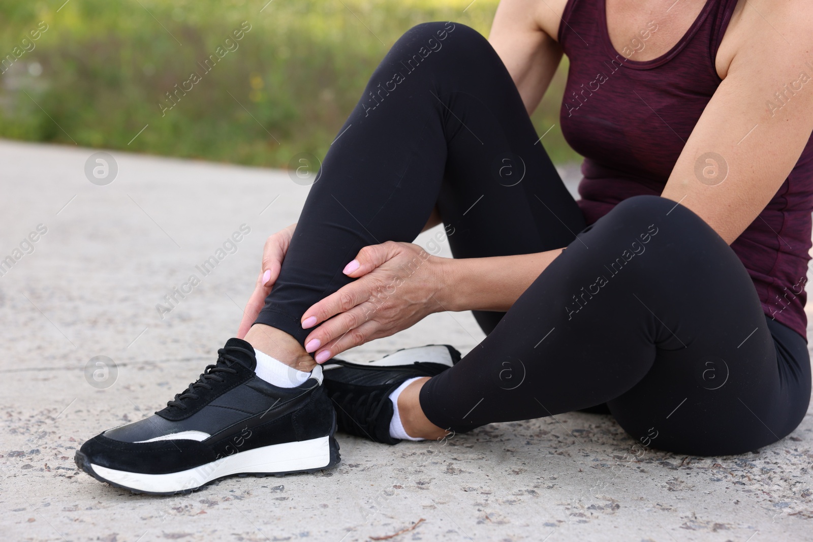 Photo of Woman suffering from foot pain outdoors, closeup