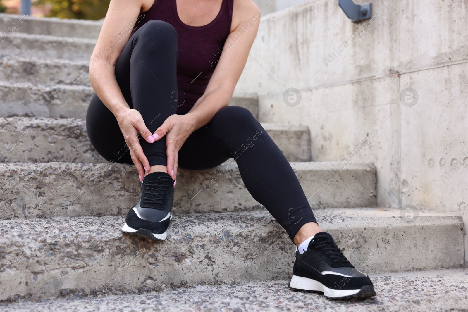 Photo of Woman suffering from foot pain on steps, closeup