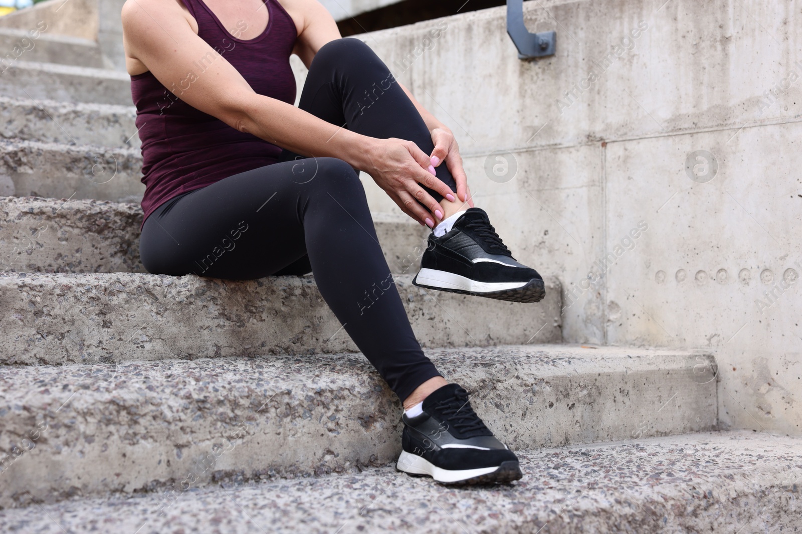 Photo of Woman suffering from foot pain on steps, closeup