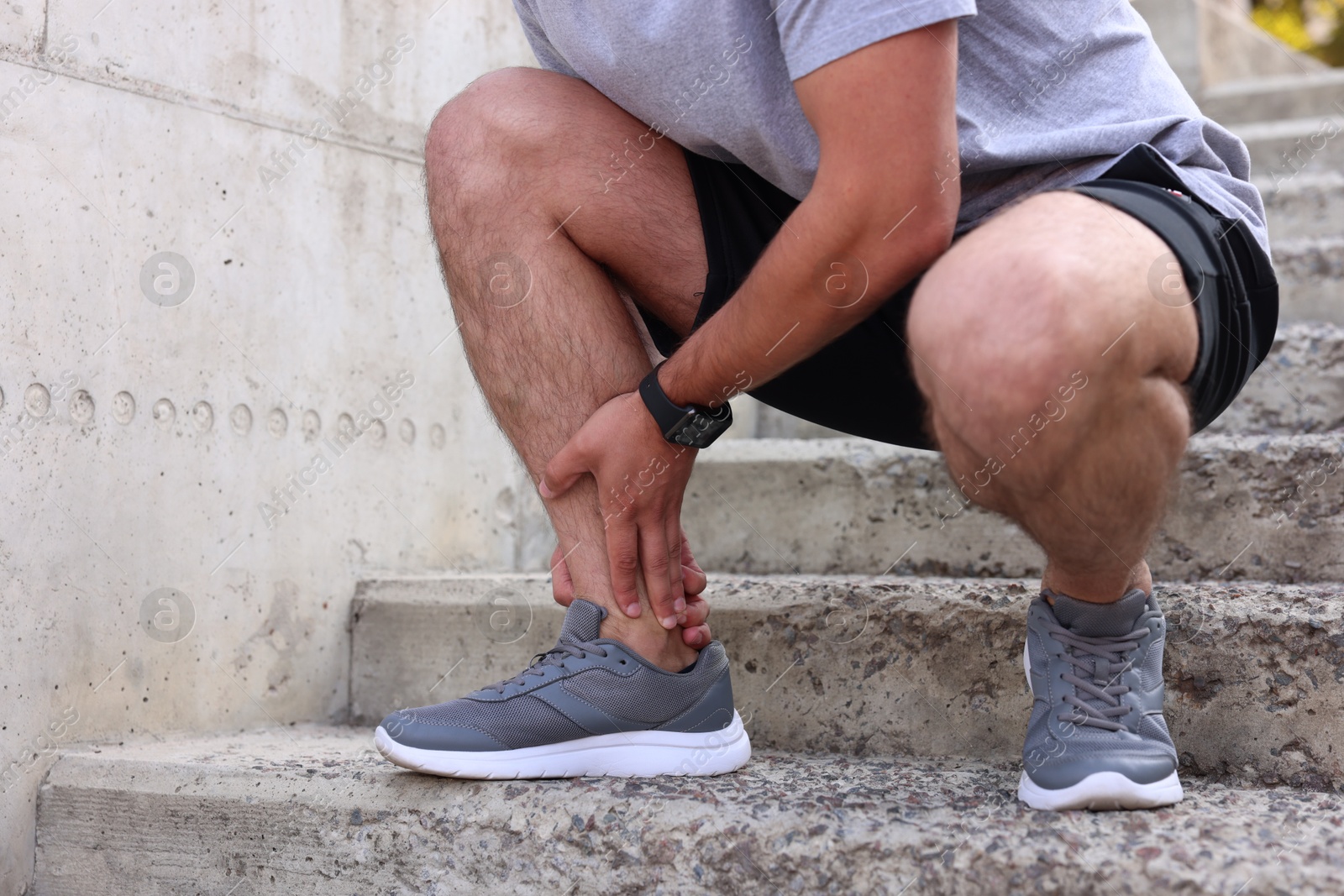 Photo of Man suffering from foot pain on steps, closeup