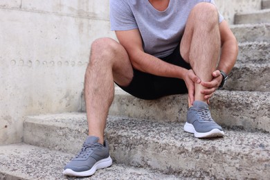 Photo of Man suffering from foot pain on steps, closeup