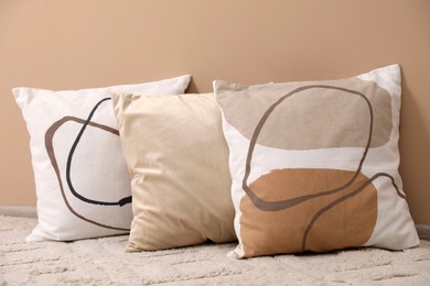 Photo of Soft pillows on floor near beige wall