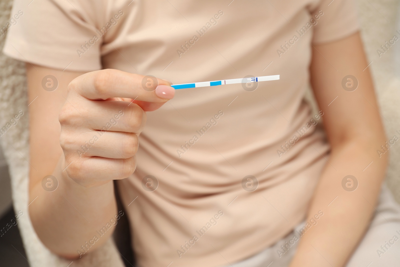 Photo of Woman holding negative pregnancy test indoors, closeup view