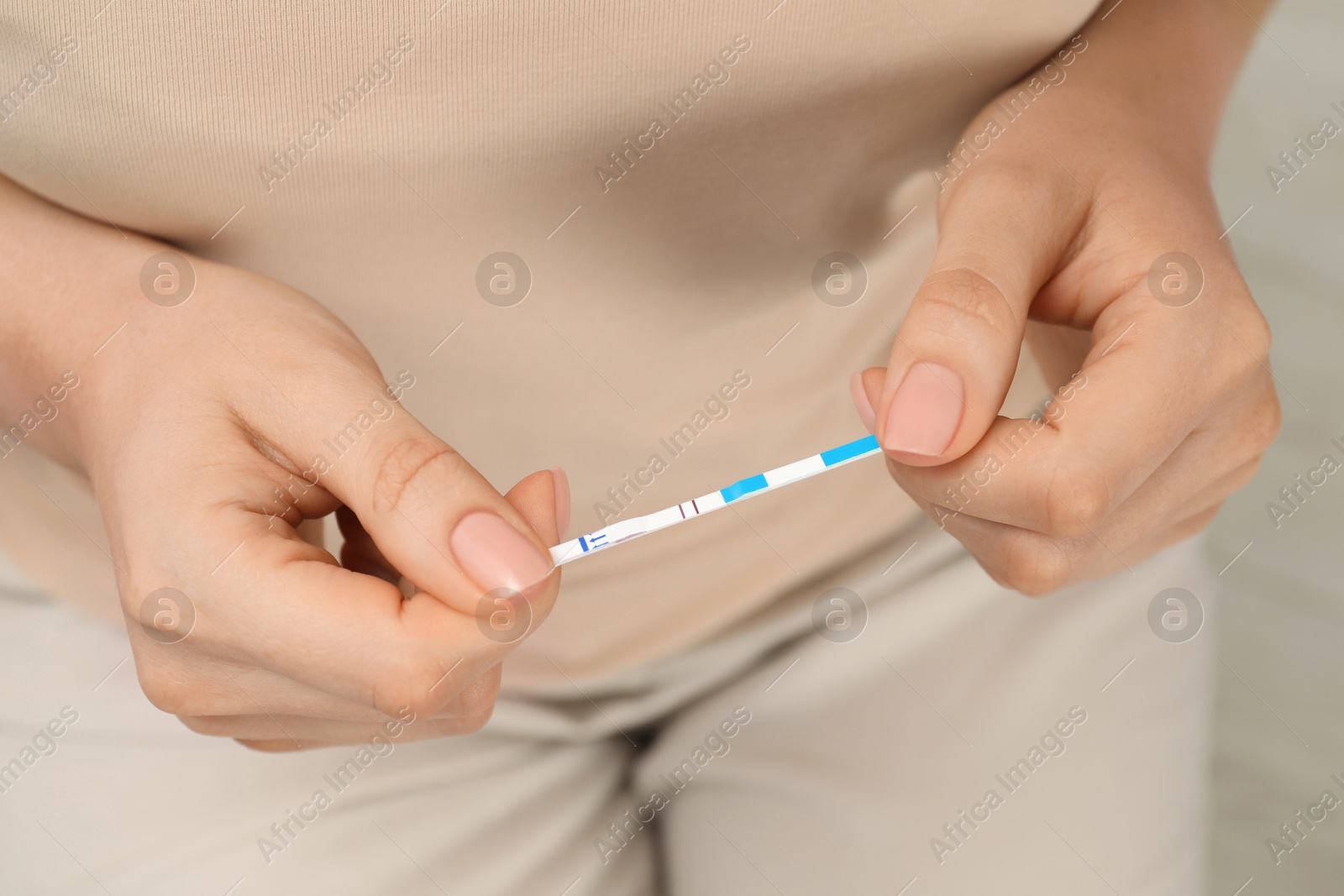 Photo of Woman holding positive pregnancy test indoors, closeup view