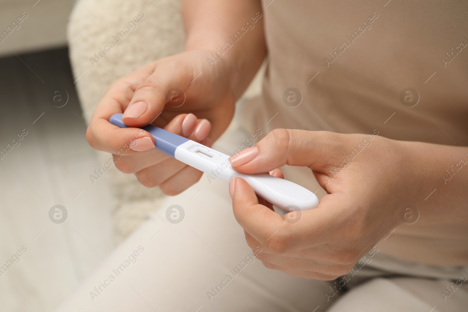 Photo of Woman holding pregnancy test indoors, closeup view