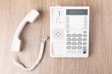 Photo of White telephone on wooden table, top view