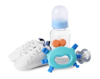 Photo of Colorful rattle, baby shoes, bottle and pacifier isolated on white