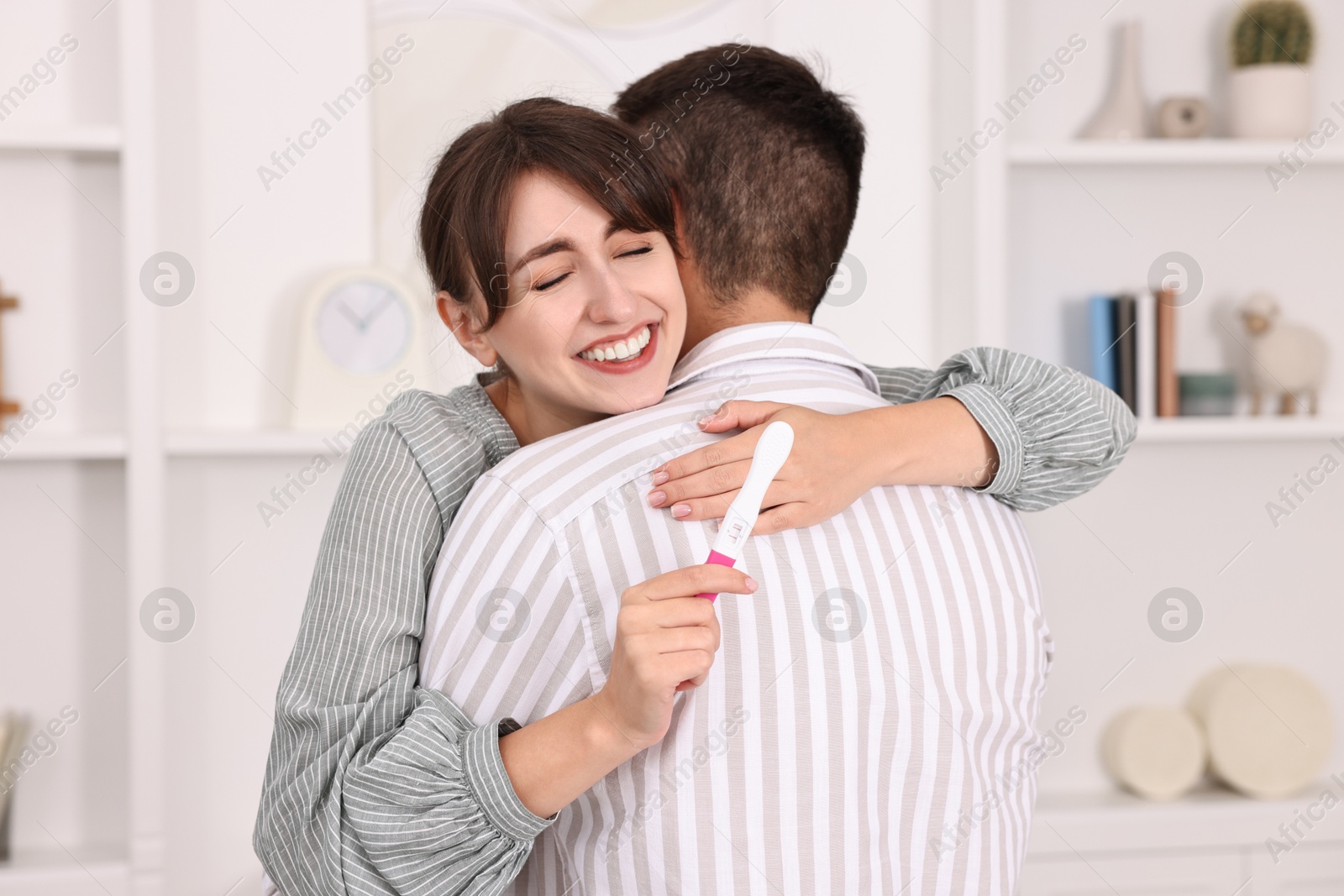 Photo of Happy young couple with pregnancy test at home