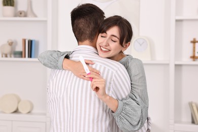 Photo of Happy young couple with pregnancy test at home