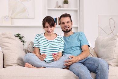 Happy young couple with pregnancy test on sofa at home