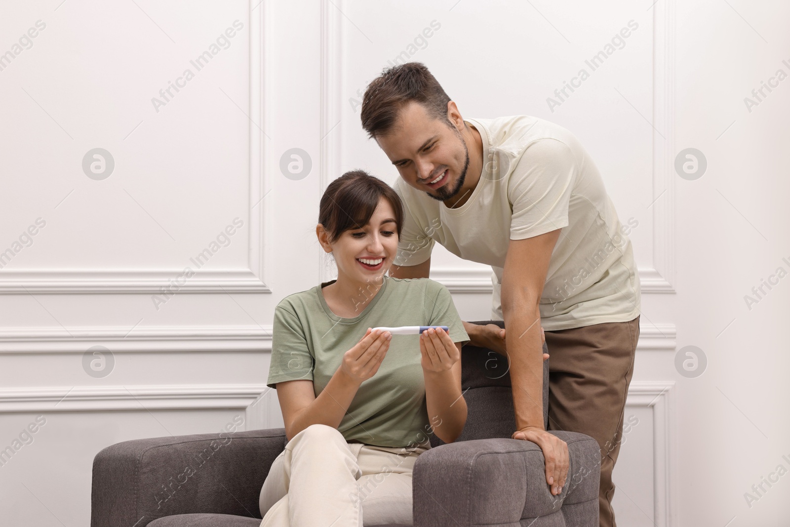 Photo of Happy young couple with pregnancy test at home